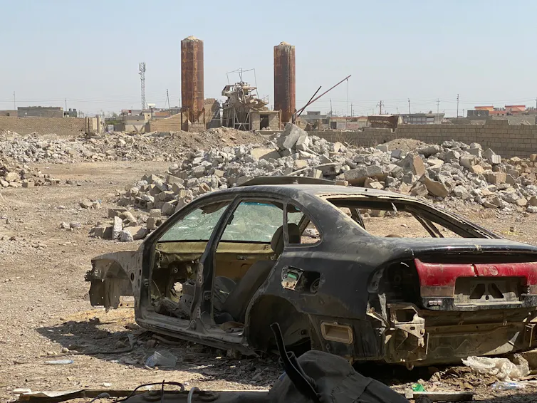 A burned-out car in front of the rubble of bombed-out buildings in Hawija, Iraq.