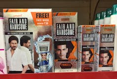 Skin lightening products on a shelf, with images of Asian males and the name 'Fair And Handsome'.