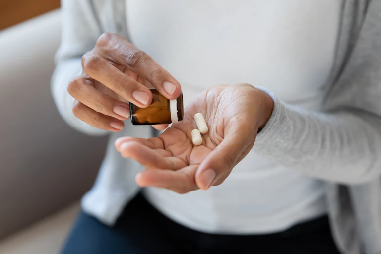 Close up of woman taking pills from a bottle.