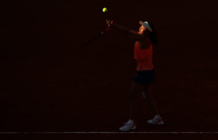 Shuai Peng tosses a tennis ball in the air and prepares to serve.