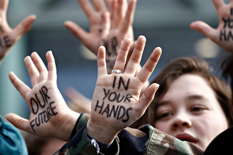 Young people at a climate protest with the words 'Our future in your hands'written on their palms