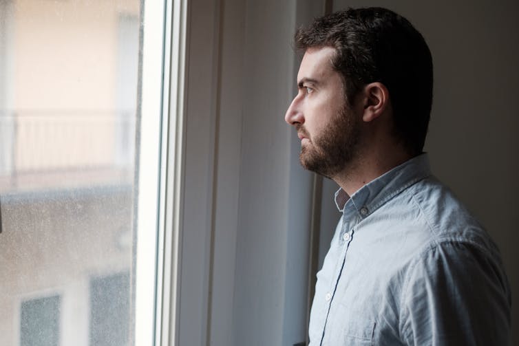 Anxious man looks out the window.