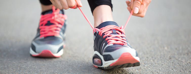 Person ties orange laces on their runners.