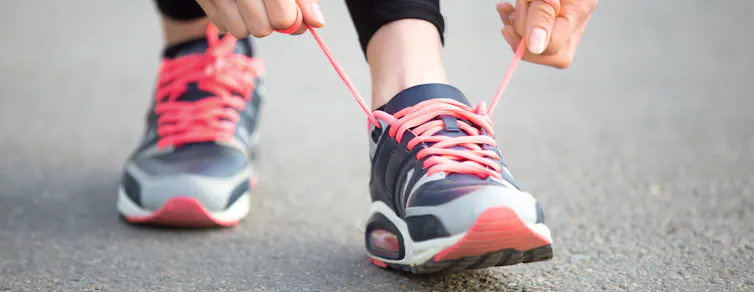 Person ties orange laces on their runners.