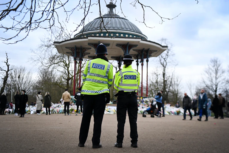 Two police officers standing in front of the floral tributes to Sarah Everard, murdered by a serving police officer.