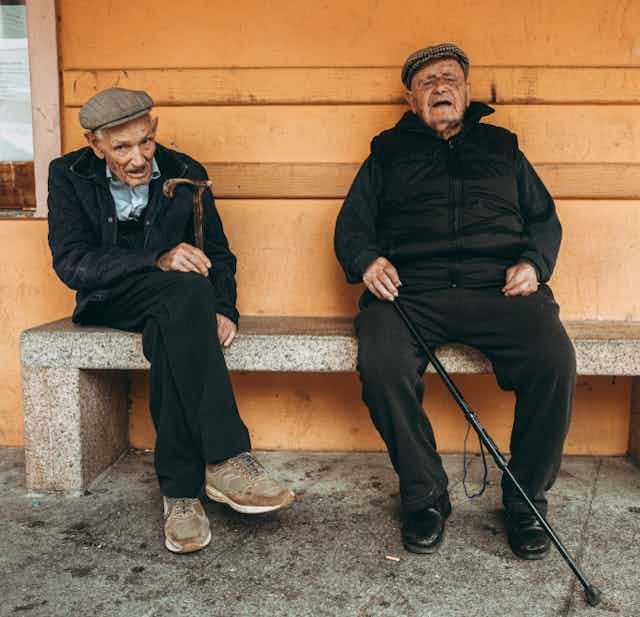 Image of two xentenarians sitting on a bench Sardinia.