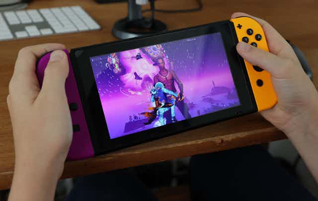 A pair of hands holding a handheld videogame