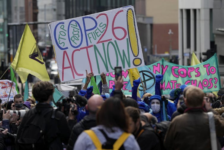 Protesters hold a large banner that reads COP25 Act Now