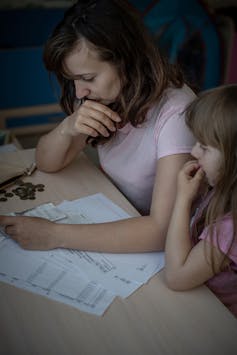 A woman and her child ponder some bills.