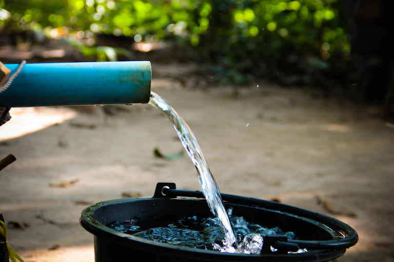 Water pours from a short blue pipe into a black bucket