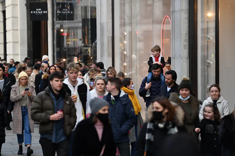 People, both masked and unmasked, on a busy shopping street