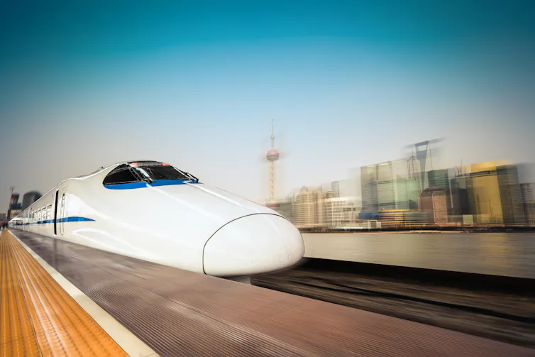 A high-speed train arrives at a rail platform.