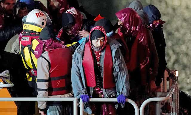 A group of people gather on a RNLI boat wearing life jackets after being rescued from the Channel.