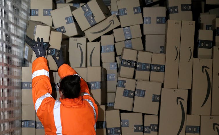 A worker packs dozens of Amazon boxes into the back of a truck.