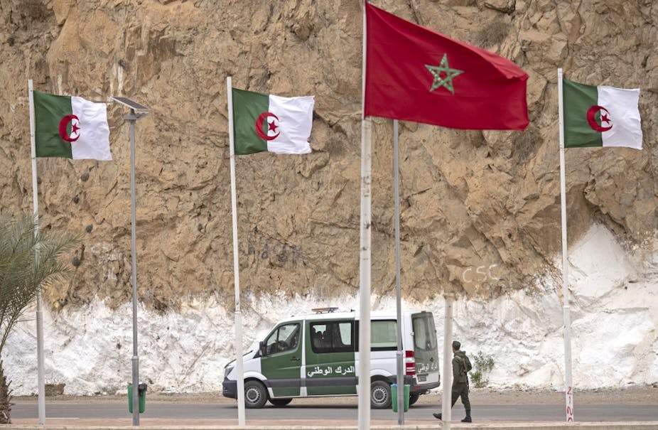 Drapeaux algériens et marocains se faisant face le long d'une route.