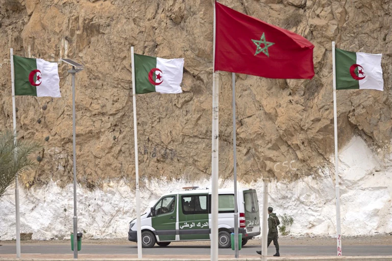 Drapeaux algériens et marocains se faisant face le long d'une route.