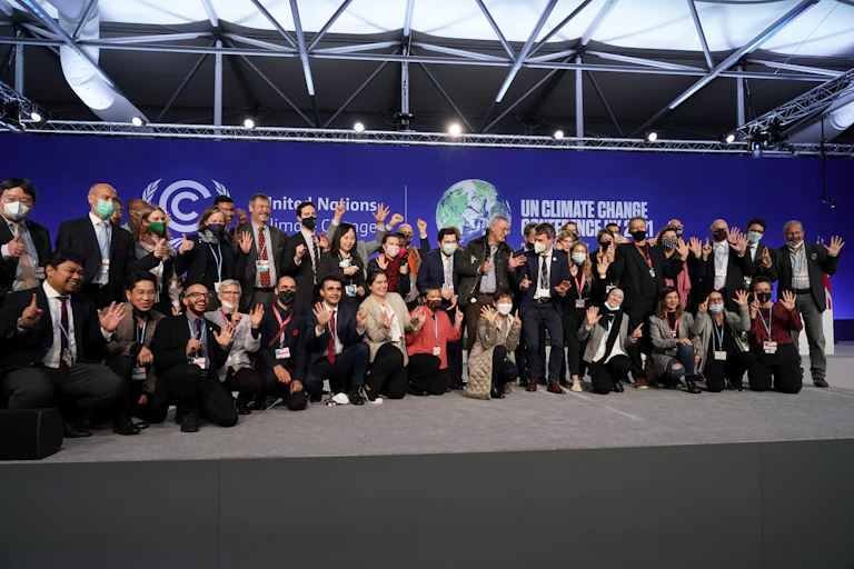 A group of people pose in front of a blue backdrop displaying the COP26 logos