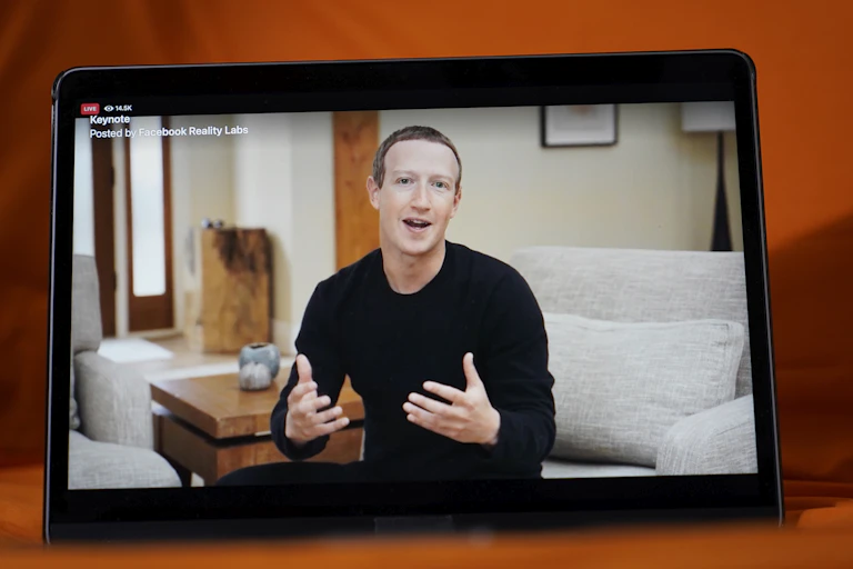 A screen shows a man in a black shirt sitting on a couch.