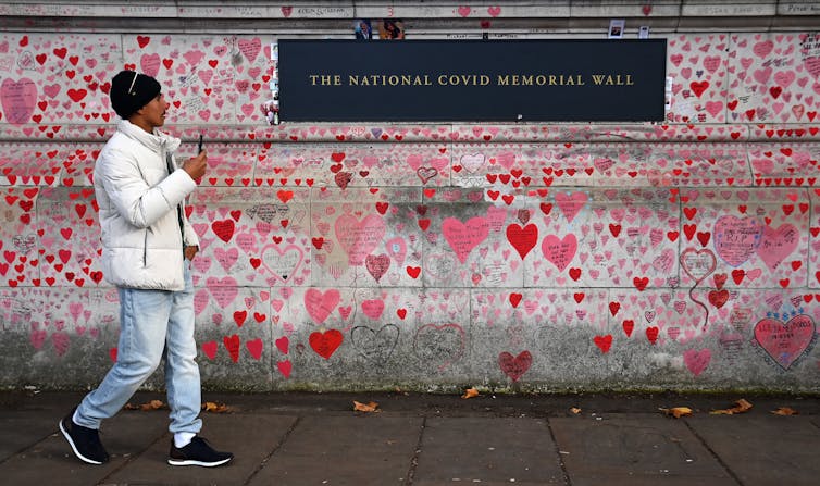 Man walks by wall covered in heart drawings