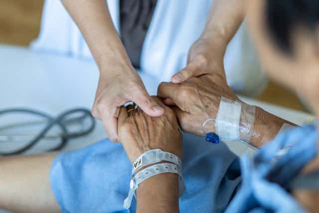 Hospital doctor holding elderly patient's hands