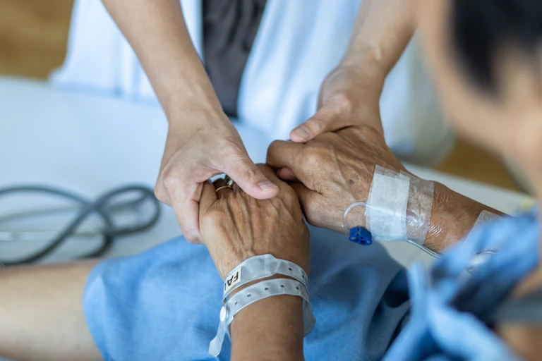 Hospital doctor holding elderly patient's hands