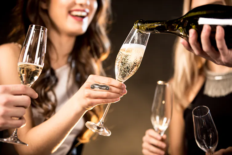 A person pours champagne into a tilted glass.