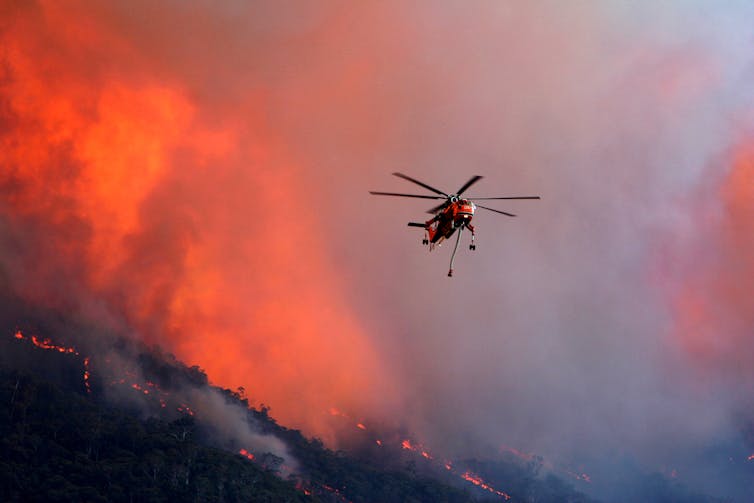a helicopter pours water on a fire