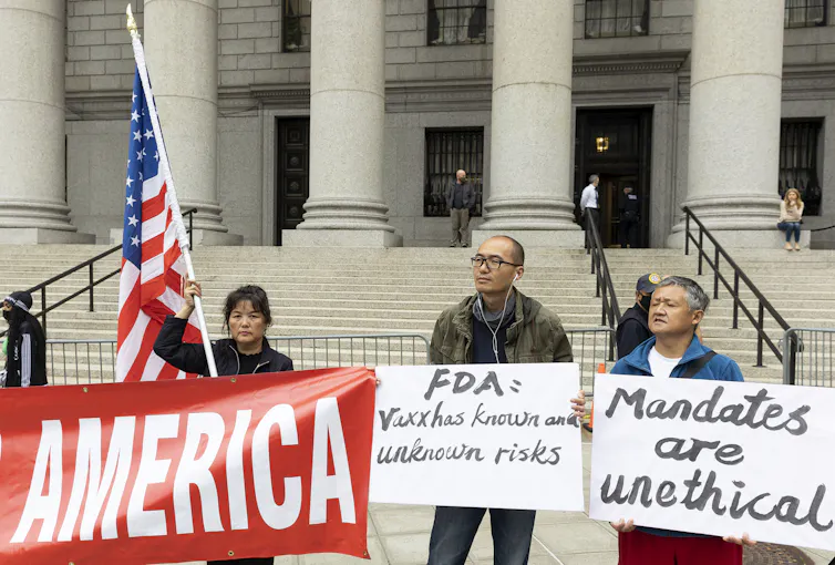 People protesting about vaccine mandates outside a courthouse in New York, carrying placards criticising the US government's vaccination plan.