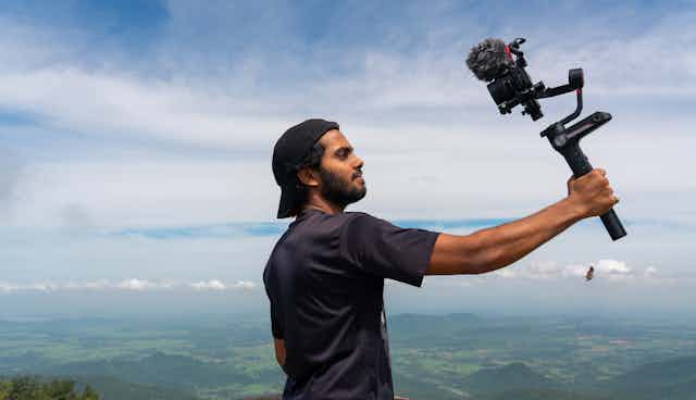 A young man holding up a camera that he is about to talk into.