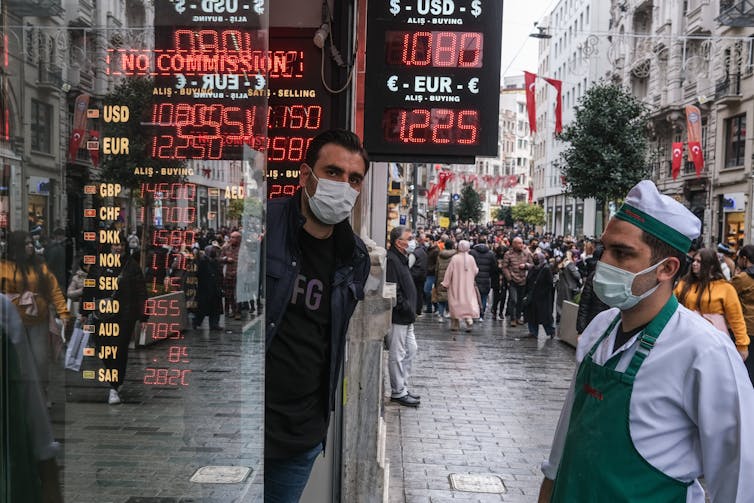 Man in COVID mask looking at exchange rates at a bureau de change