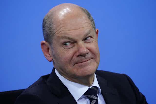 Olaf Scholz smiling at a press conference. 