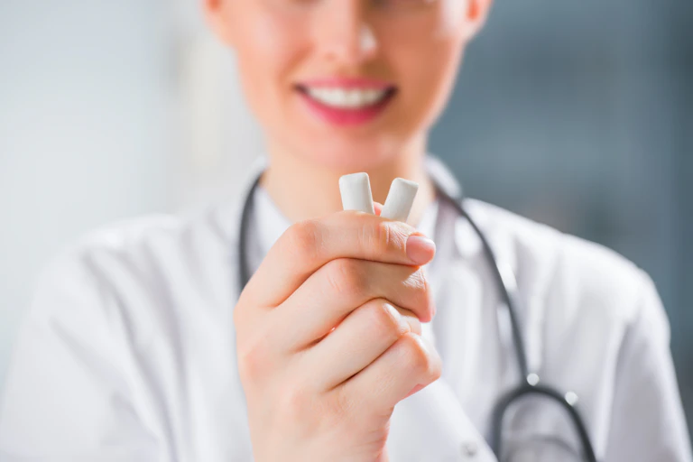 A doctor or dentist holds two pieces of chewing gum.