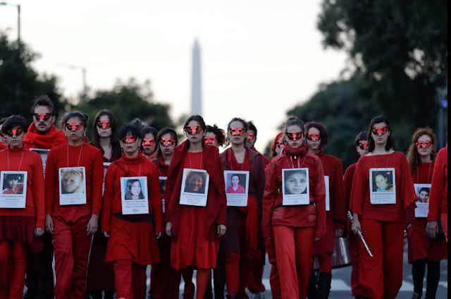 Des femmes et un homme portent des habits rouge dans une manifestation