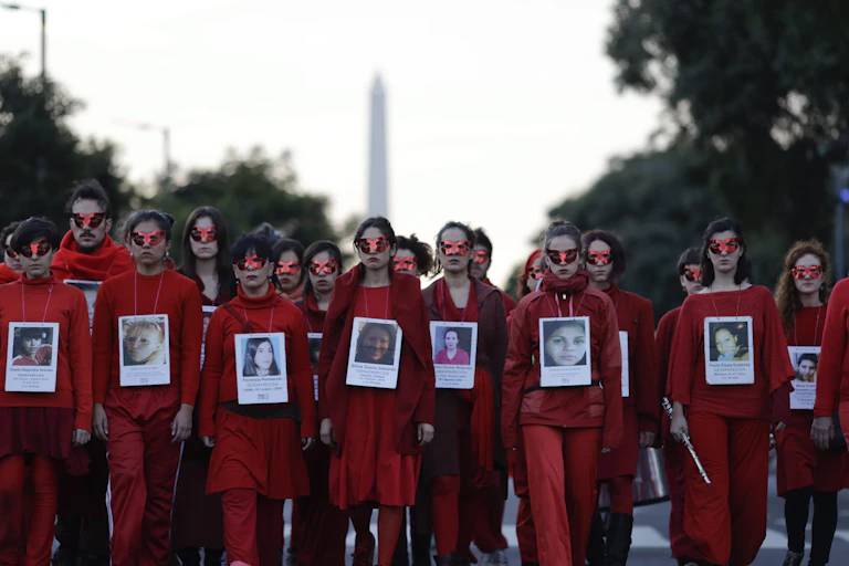 Des femmes et un homme portent des habits rouge dans une manifestation