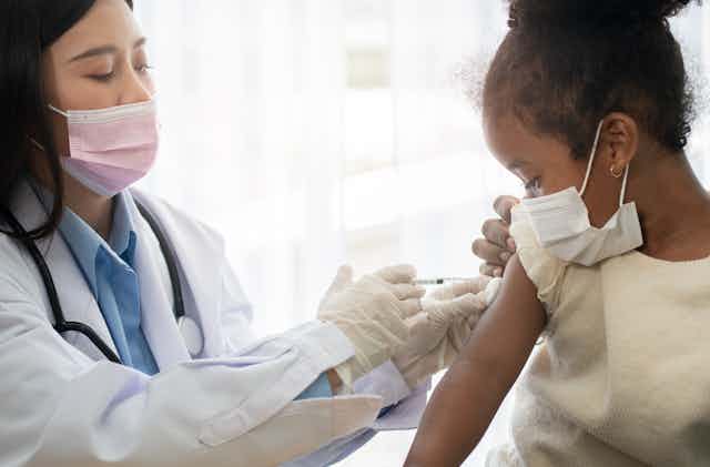 A doctor vaccinating a young girl against COVID