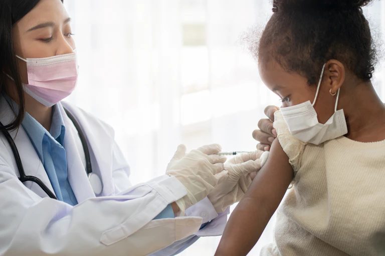 A doctor vaccinating a young girl against COVID