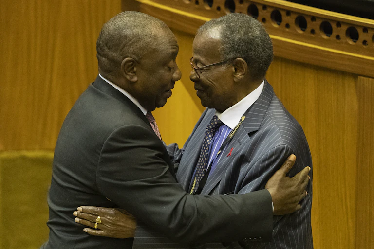 Two men wearing suits embrace each other