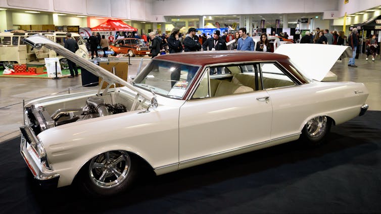 A large cream-coloured car with a brown roof with its trunk and hood open.