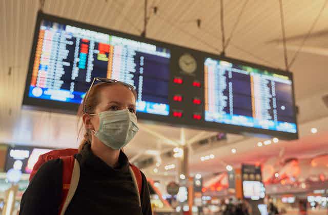 Photo d’une femme portant un masque chirurgical dans un aéroport