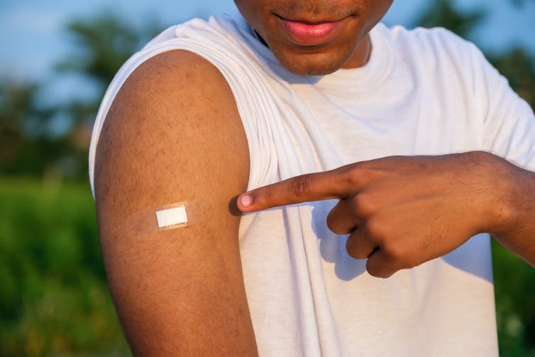 Boy points to his bandaid, after having a vaccination.
