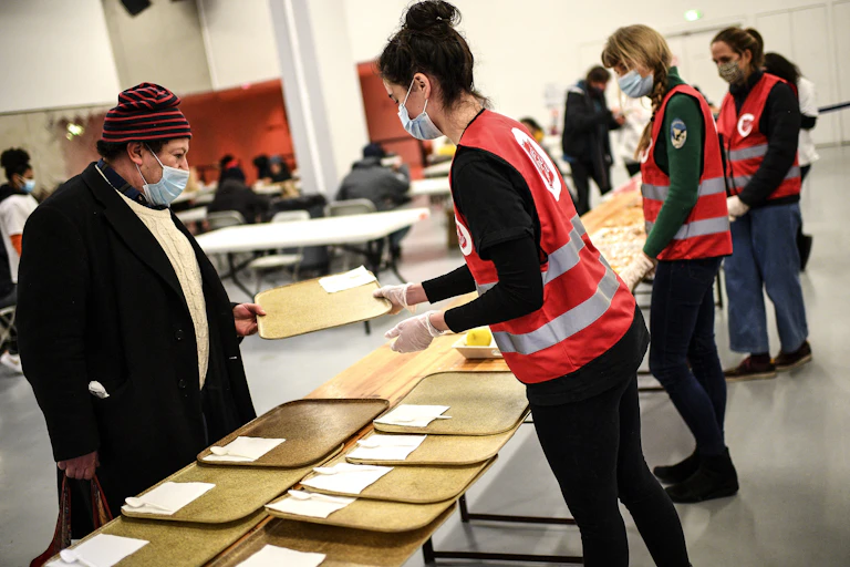 Des bénévoles offrent un petit-déjeuner à des personnes dans le besoin lors d'une opération de distribution alimentaire menée par la fondation L'Armée du Salut à Paris, le 12 février 2021.