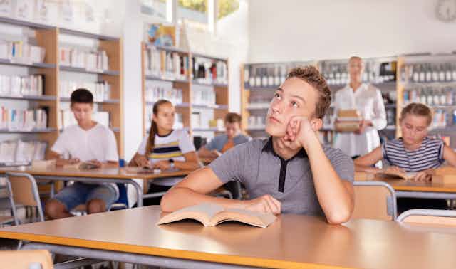 Teenage boy with book in class looking bored