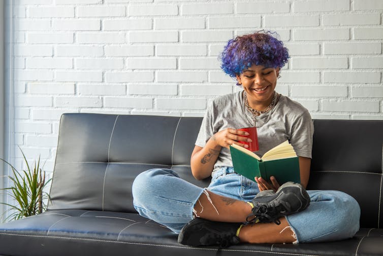 Young woman smiling reading book on sofa