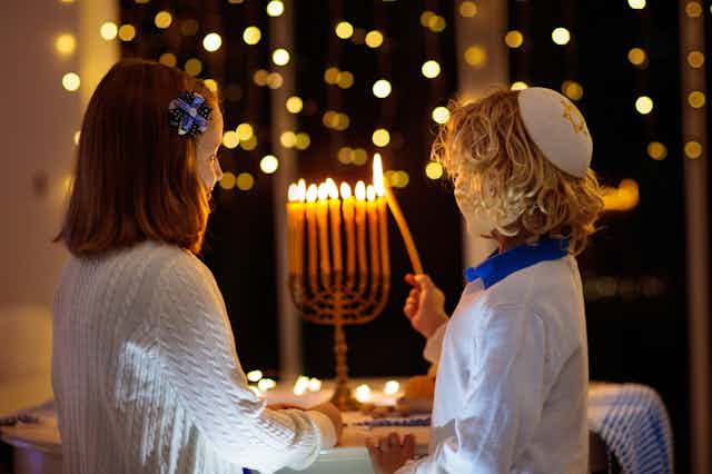 Two children light a menorah.