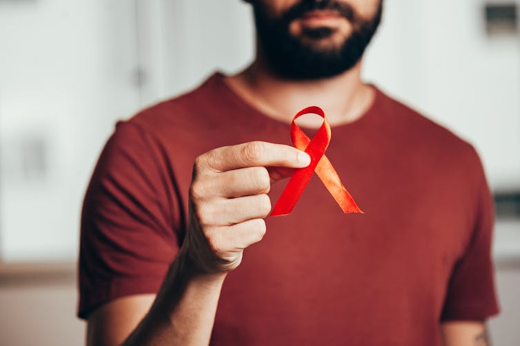 Person holding red ribbon.