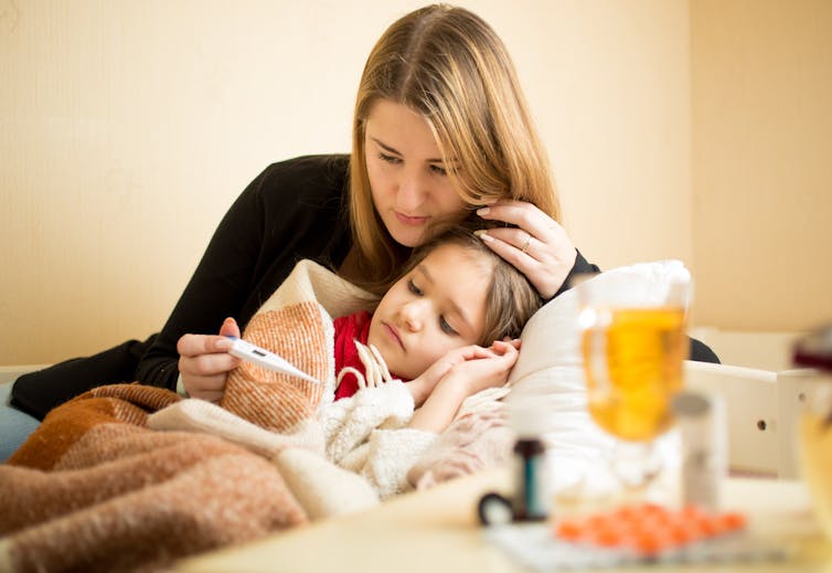 Mother takes her sick child's temperature.