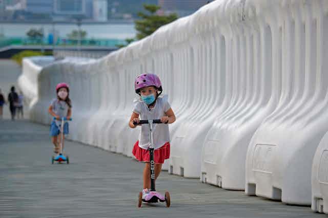 Children on scooters wearing masks