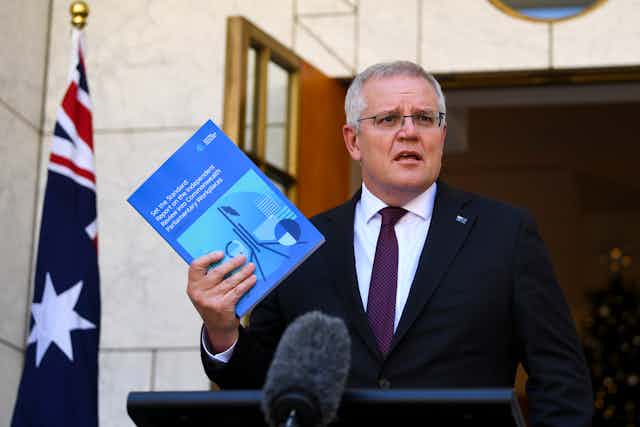 Prime Minister Scott Morrison holding a copy of the Jenkins report.