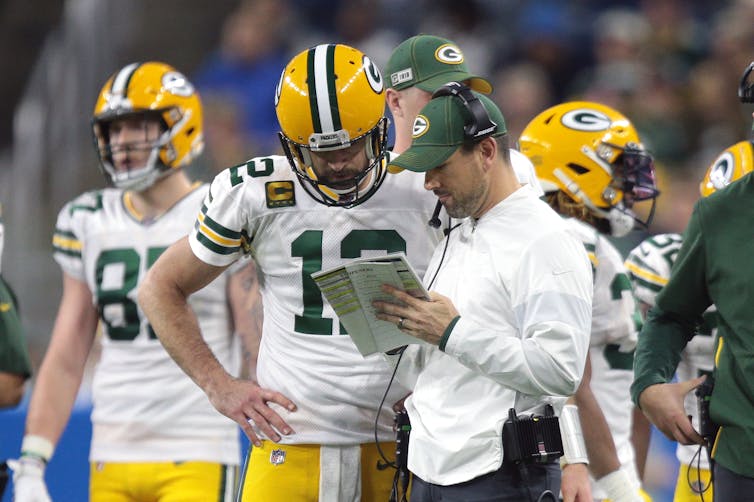 Rodgers confers with a coach on the sidelines
