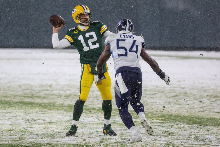 Rodgers initiates a pass with an opposing player coming at him